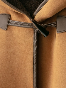 Detail of horn toggle closure on a warm suede coat with leather binding and stitching