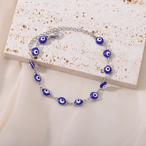Detailed view of evil eye bracelet with blue beads and silver chain on stone surface