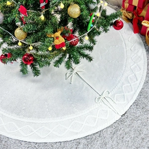 Détail de la jupe de sapin de Noël en tricot blanc avec motif losange et rubans d'attache