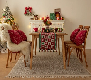 Detail view of red and green plaid Christmas table runner with tassels and elk motifs