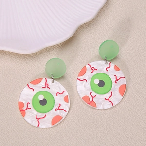 Close-up of quirky green eyeball acrylic earrings on a textured beige leather surface