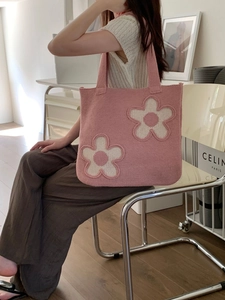Pink knitted tote bag with white flower patterns shown in a bright home setting