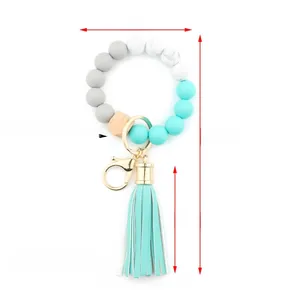 Macro detail of silicone bead keychain with wooden hexagon and teal leather tassel