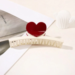 Detail of a cream hair claw clip with glossy red heart accents for elegant hair styling