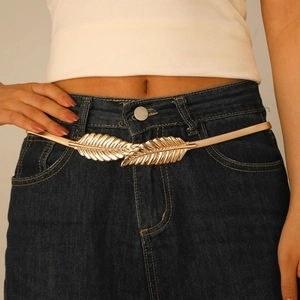 Cintura elastica dorata da donna con fibbia a foglia su top bianco e gonna di jeans