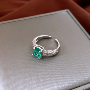 Dettaglio anello con zircone verde smeraldo e pavé di diamanti su fascia d'argento