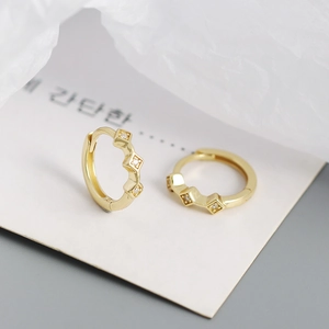 Macro view of gold rhombus-patterned earrings with sparkling cubic zirconia inlay