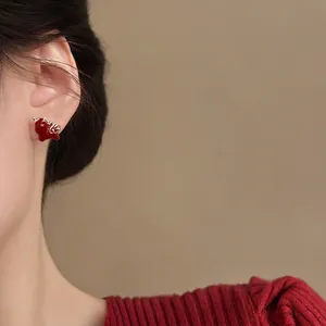 Elegant 18k gold plated red enamel pony stud earrings worn by a model in red knitwear