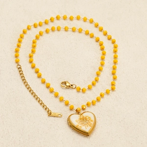 Titanium steel necklace with yellow beads and gold heart locket containing dried flowers