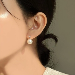 Close-up of 925 silver pearl earring with cubic zirconia on model ear profile