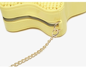 Detail of yellow star-shaped PVC bag showing gold metal zipper and chain strap texture