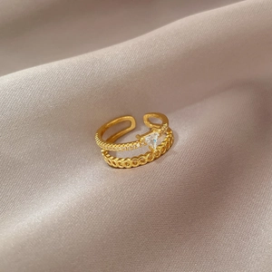 Detailed close-up of a double-layer gold ring with a sparkling triangle zircon stone