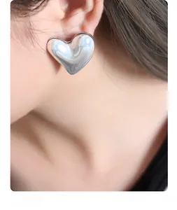 Detailed close-up of a silver heart stud earring with a pearlescent finish on a model