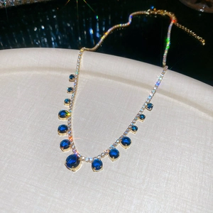 Macro shot of gold necklace with dark blue round gemstone and sparkling zircons