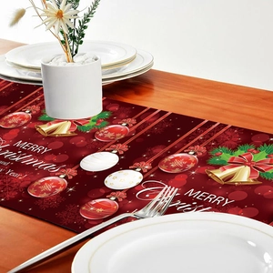 Red Christmas table runner with festive balls and bells on a rustic wooden dining table