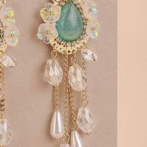Detail of floral earrings with green teardrop stone, crystals and pearl tassels
