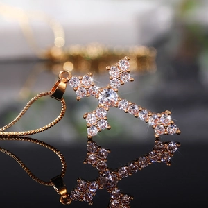 Macro shot of gold cross pendant with cubic zirconia and its reflection on black glass