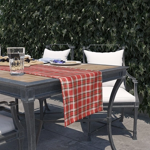 Nordic style red and white plaid table runner on a wooden outdoor dining table with ivy
