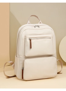 Detailed close-up of a beige nylon backpack featuring metal zippers and leather pullers