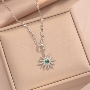 Elegant sunburst star necklace with green gem and white diamonds in a premium jewelry box