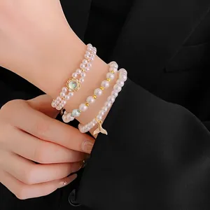 Three-layer pearl bracelet set with moonstone and pavé fish tail charm on black suit