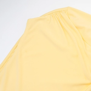 Close-up of pleated shoulder detail on a slim-fit yellow long sleeve knit dress