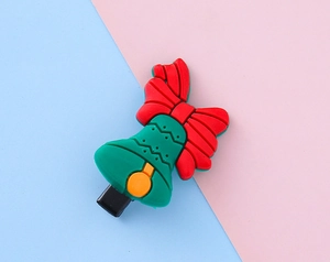 Détail d'une pince à cheveux de Noël avec nœud rouge et cloche verte sur fond coloré