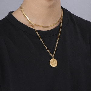 Detail of a double-layered gold snake chain necklace with a vintage round religious pendant