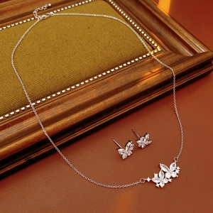 Vue macro d'une parure collier et boucles d'oreilles papillon argenté sur cuir