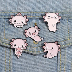 Set of five cute pink axolotl enamel pins in various poses on blue denim fabric