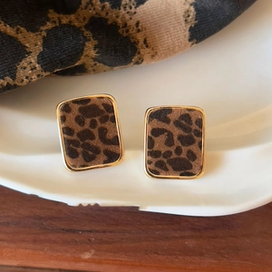 Close-up of vintage leopard print rectangular earrings on elegant ceramic tray