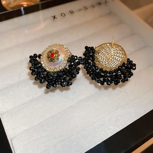 Detail view of floral stud earrings with black beads and gold mesh backing on display box
