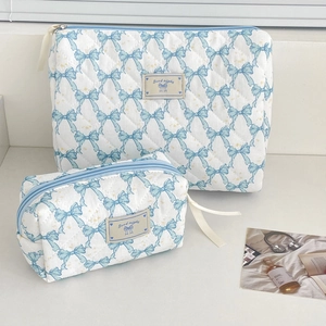 Quilted white toiletry bags with light blue bow patterns in large and small sizes