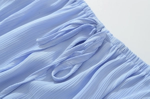 Détail du tissu plissé bleu clair et de la ceinture assortie sur la robe élégante