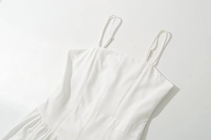 Detailed view of white spaghetti strap dress featuring delicate lace stitching and slim waist