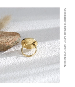Detail of wide round gold plated ring showing hammered metal texture and luster