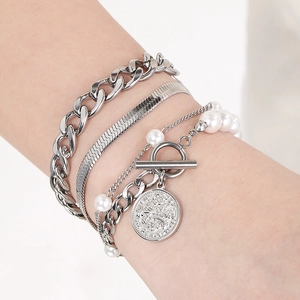 Detail of silver layered bracelet set with coin charm and pearl bead on model wrist