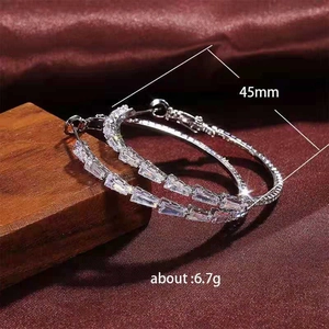 Silver C-shaped hoop earrings with baguette cubic zirconia on a rustic backdrop