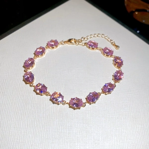 Detailed view of pink oval zircons set in a gold chain bracelet with adjustable lobster clasp