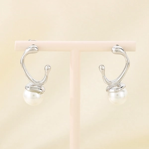 Detailed shot of French vintage silver bow earrings with white pearls on a display stand