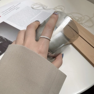 Detail of shimmering sand textured S925 sterling silver ring worn on hand with a glass