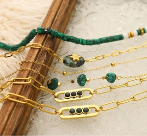 Close-up of gold layered bracelets with green malachite and black onyx on white lace