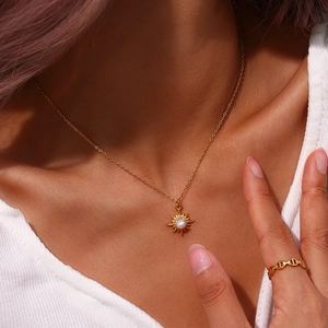 Detail of 18K gold plated necklace with starburst pearl pendant on female model