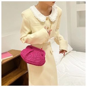 Pink woven straw clutch bag with gold chain strap shown on beige tweed outfit detail