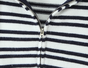 Detail der blau-weiß gestreiften Stricktextur und des silbernen Metallreißverschlusses