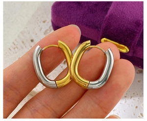 Detail of two-tone gold and silver oval hoop earrings with polished steel finish