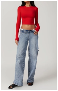 Close-up of a red cropped long-sleeve top paired with ripped wide-leg jeans and folded waist
