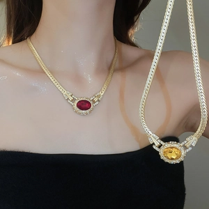 Detailed view of vintage gold snake chain necklaces with red and yellow oval gemstones