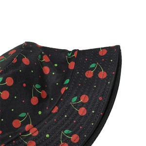 Close-up of black sun hat featuring embroidered red cherry patterns and fine stitching