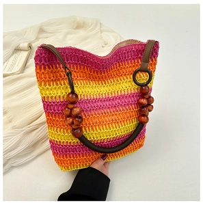 Detail of rainbow straw bucket bag featuring pink and yellow stripes with wooden bead handle